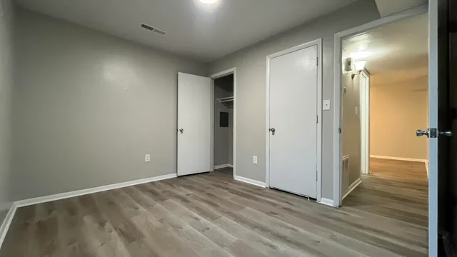 an empty room with wooden floor and a bathroom