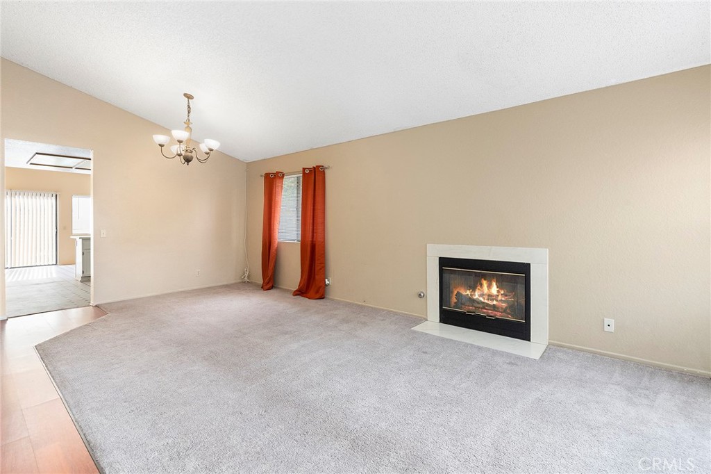 3665 Anchorage Street Hemet, CA 92545 - Photo 4 of 23 an empty room with a fireplace and a chandelier