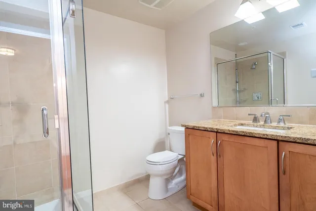 a bathroom with a granite countertop sink a toilet and a mirror