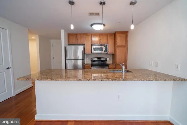 a large kitchen with granite countertop a stove a sink a counter space and cabinets