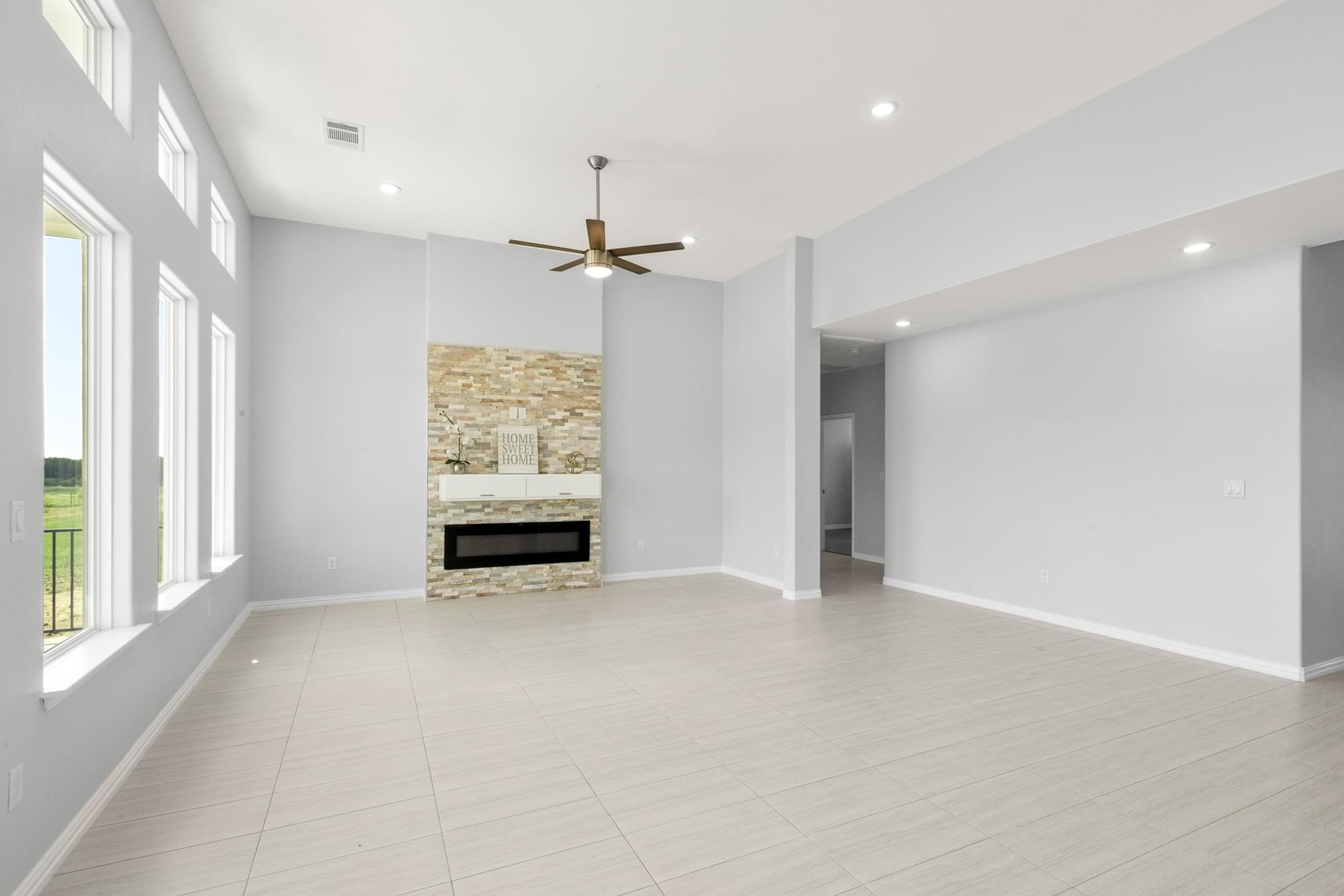 1136 County Road 484 Elgin, TX 78621 - Photo 14 of 37 Unfurnished living room with plenty of natural light, a glass covered fireplace, recessed lighting, a ceiling fan, and light tile patterned floors