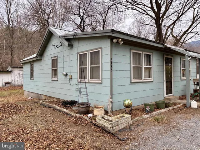 a backyard of a house with wooden fence and large trees