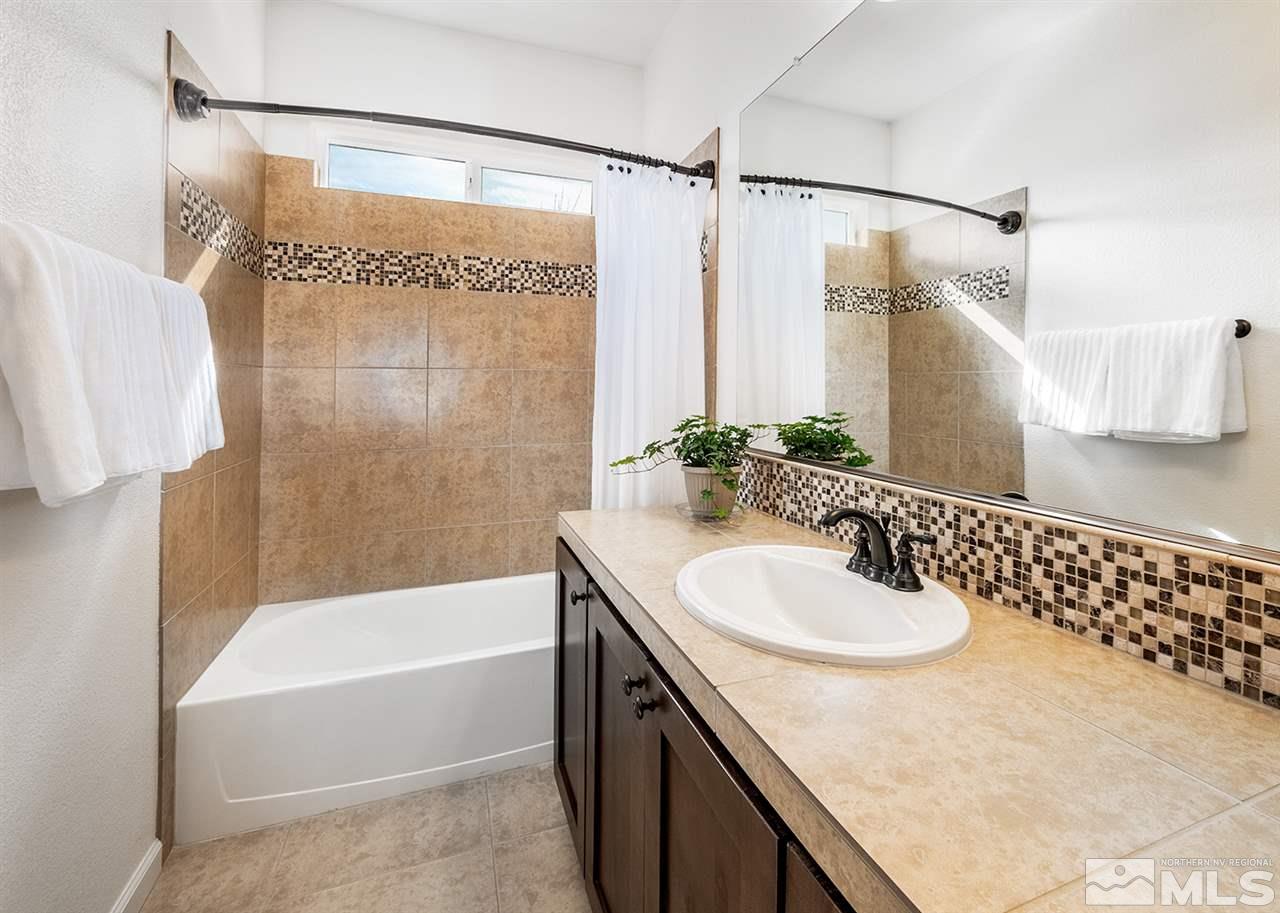 1640 Elk Run Trail Reno, NV 89523 - Photo 38 of 40 a bathroom with a granite countertop sink a mirror a bathtub and shower