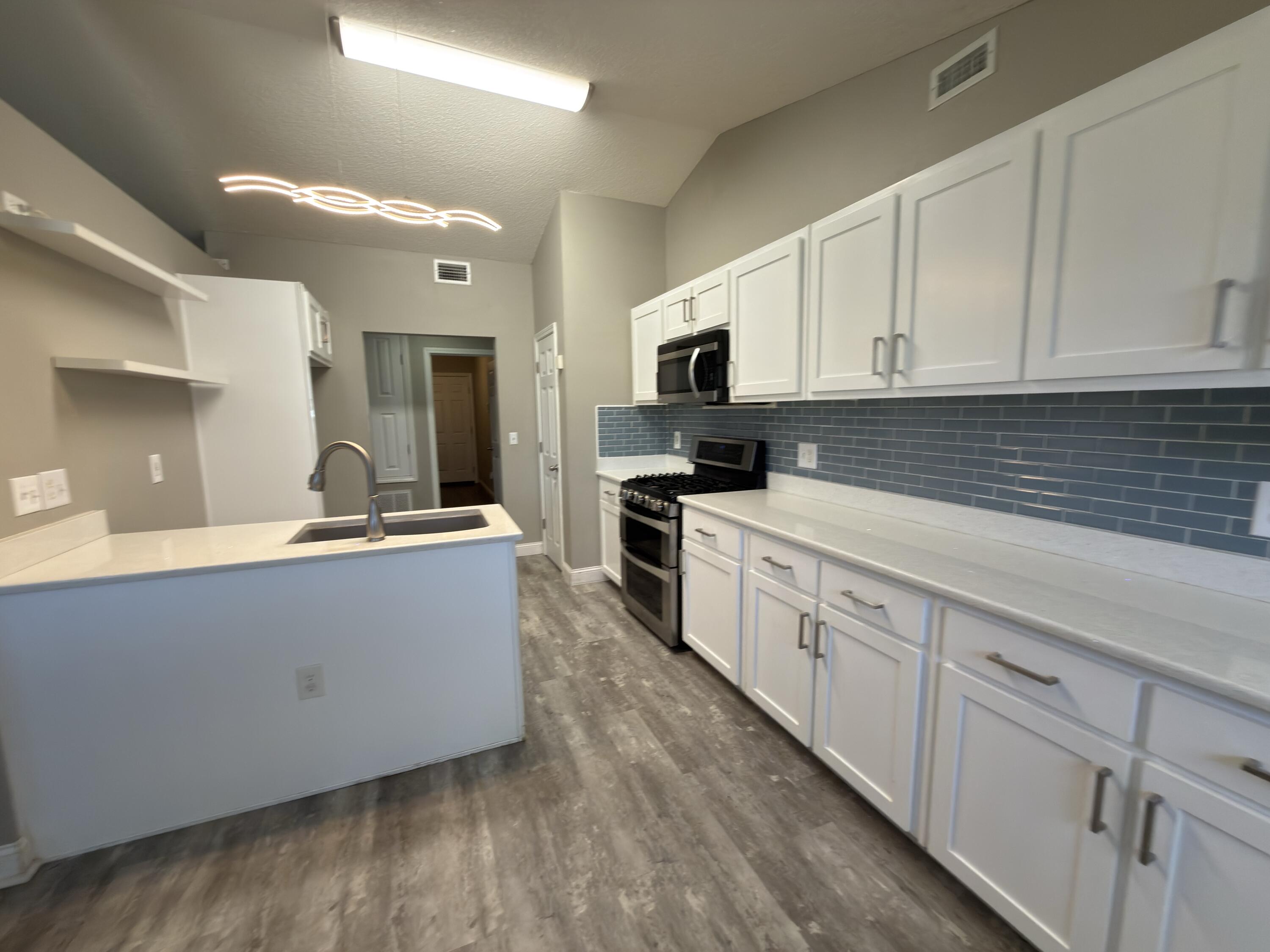 2673 Paddock Circle Crestview, FL 32536 - Photo 3 of 26 a large kitchen with cabinets wooden floor and stainless steel appliances