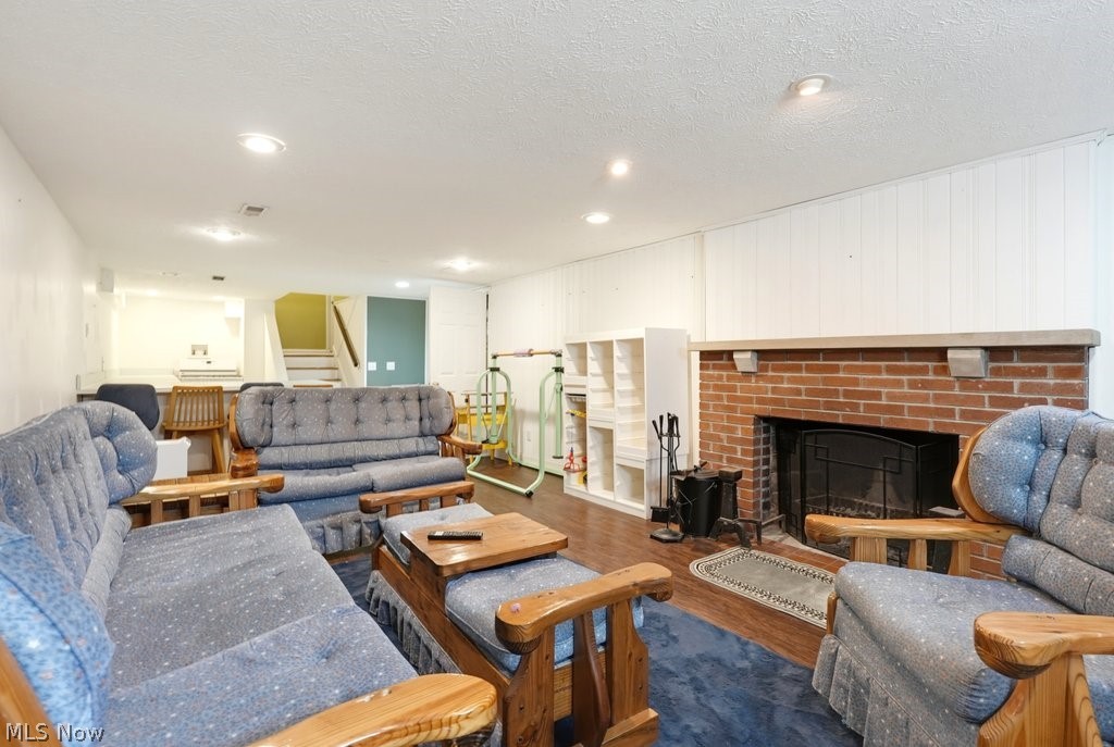 149 North Medina Line Road Akron, OH 44333 - Photo 21 of 42 Brick fireplace with a stone mantel, recessed lighting, wood-finish flooring, and white paneled walls
