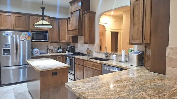 a kitchen with granite countertop a sink stainless steel appliances and cabinets
