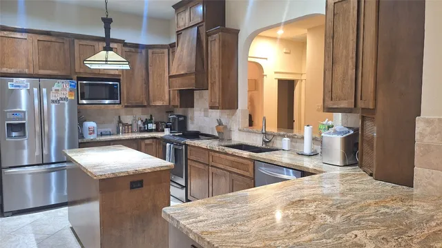 a kitchen with granite countertop a sink stainless steel appliances and cabinets