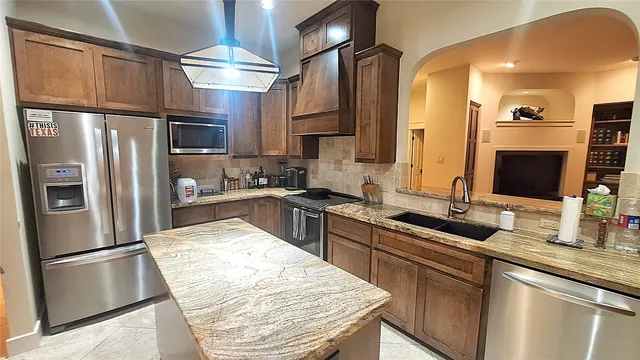 a kitchen with stainless steel appliances granite countertop a refrigerator a sink dishwasher a stove with wooden floor