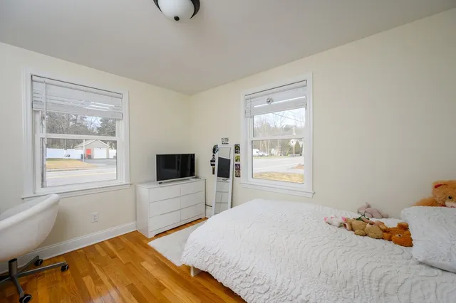 a bedroom with a bed and flat tv screen on the dresser