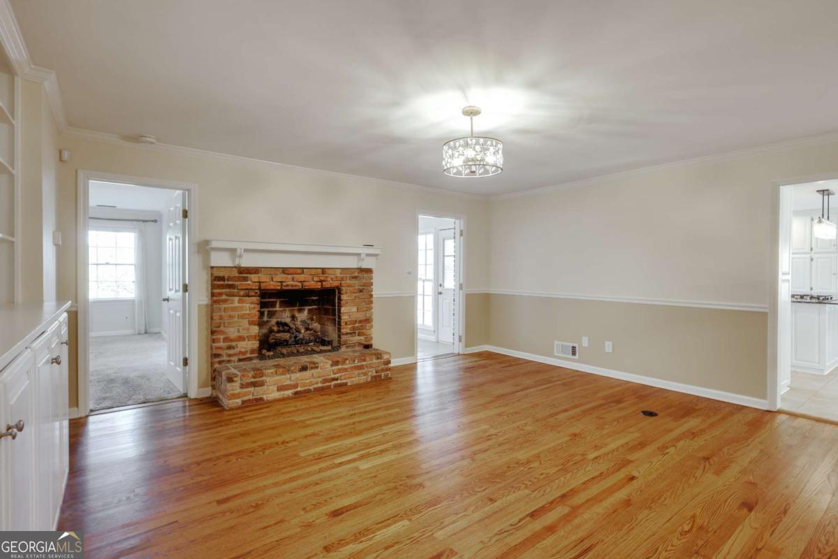 206 Fortson Drive Athens, GA 30606 - Photo 12 of 38 an empty room with wooden floor a fireplace and chandelier