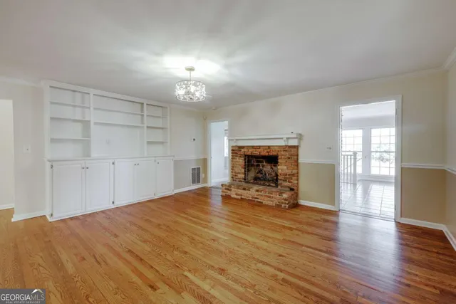 an empty room with wooden floor fireplace and windows