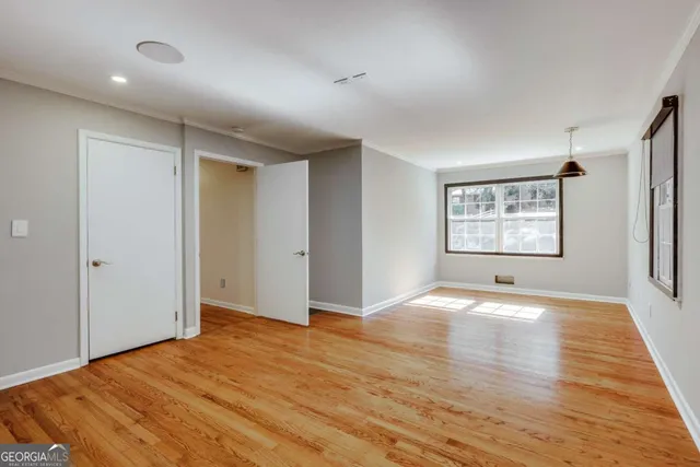 a view of an empty room with window and wooden floor