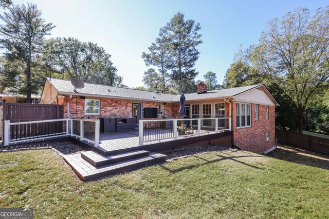 a view of a house with a yard chairs and wooden fence