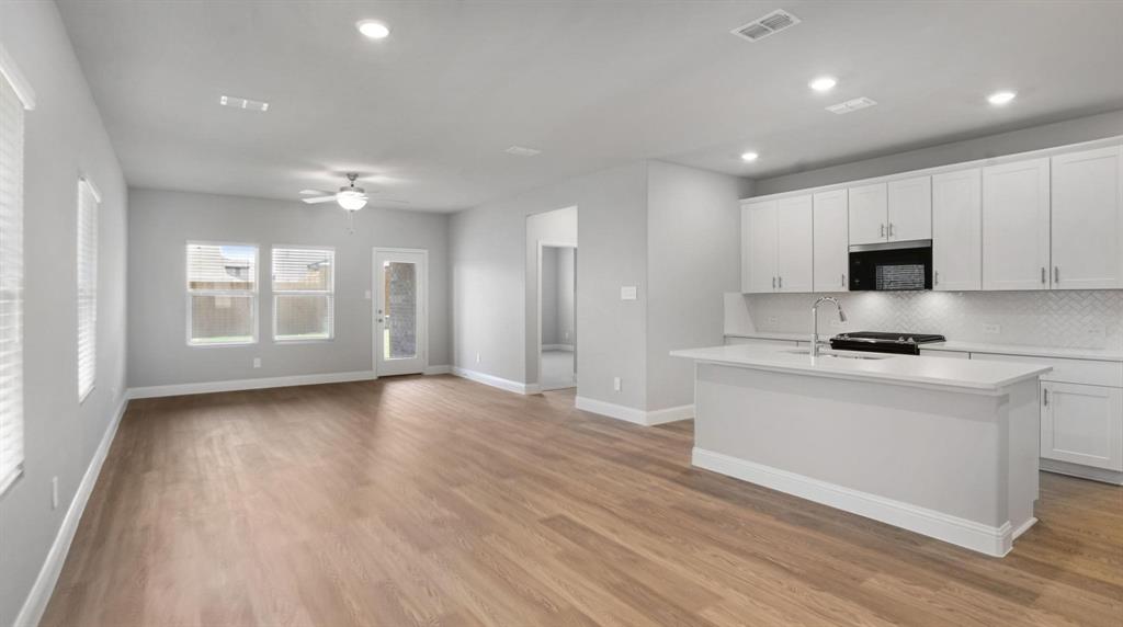 1728 Arches Road Anna, TX 75409 - Photo 2 of 11 Kitchen with an island with sink, white cabinetry, black appliances, decorative backsplash, and light wood-style floors