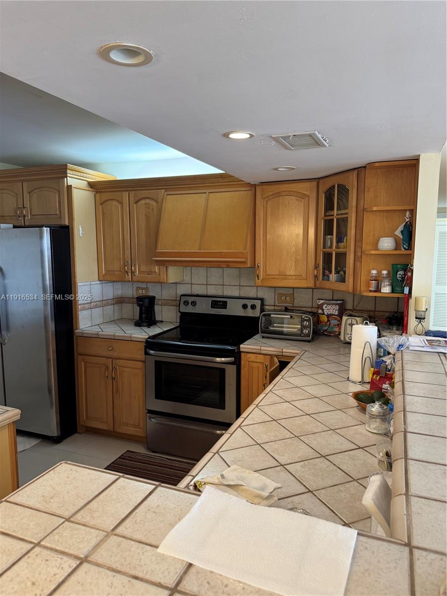 800 Northeast 195th Street, Unit 714 Miami, FL 33179 - Photo 8 of 17 a kitchen with stainless steel appliances kitchen island granite countertop a stove a sink and a refrigerator