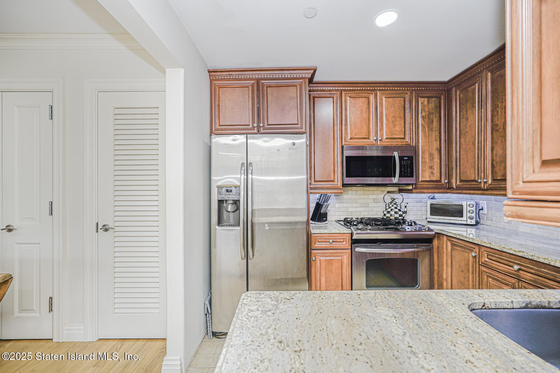 155 Bay Street, Unit 2L Staten Island, NY 10301 - Photo 19 of 32 a kitchen with stainless steel appliances granite countertop a stove top oven a sink dishwasher and a refrigerator with wooden floor