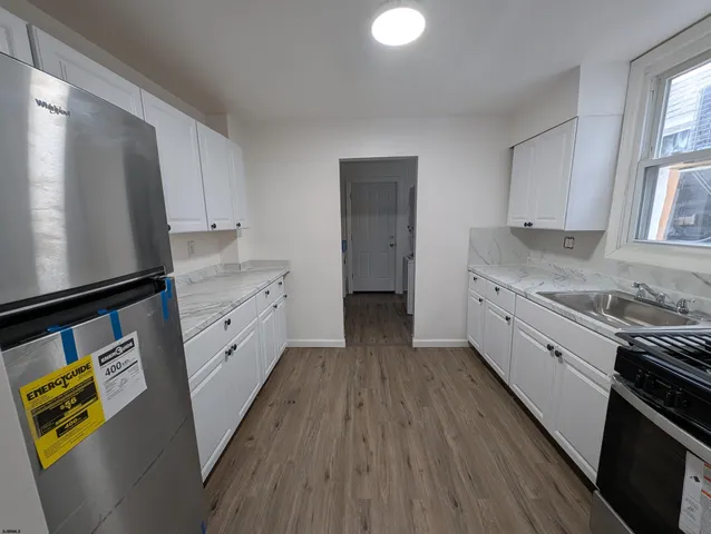 a kitchen with granite countertop a sink cabinets stainless steel appliances and a window