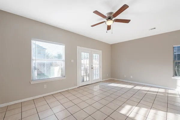 a view of an empty room with window and chandelier fan