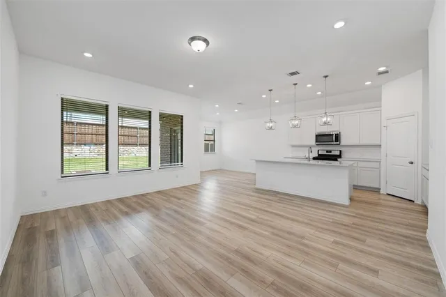 a view of kitchen with kitchen island wooden floors and stainless steel appliances