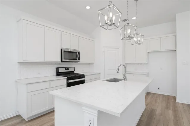 a kitchen with stainless steel appliances a kitchen island hardwood floor sink and stove
