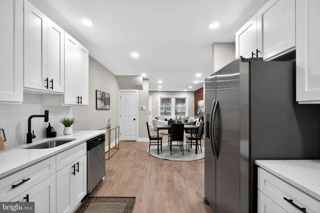 a kitchen with stainless steel appliances kitchen island granite countertop a refrigerator a sink a stove and a cabinets with wooden floor