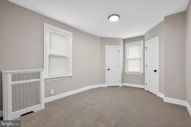 a view of an empty room with closet and a window