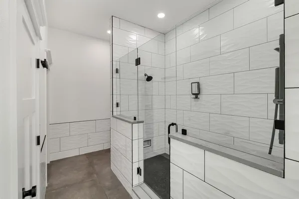a spacious bathroom with double vanity sink a two mirror a window and a bathtub