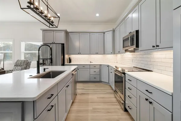 a kitchen with kitchen island granite countertop a sink cabinets and stainless steel appliances