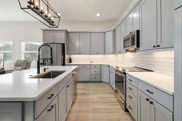 a kitchen with kitchen island granite countertop a sink cabinets and stainless steel appliances