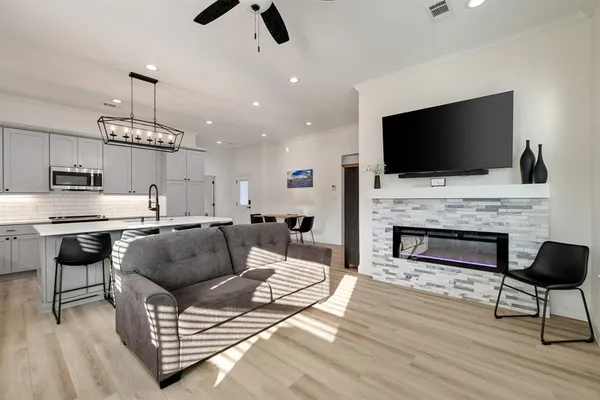 a kitchen with stainless steel appliances kitchen island granite countertop a refrigerator oven a sink dishwasher and white cabinets with wooden floor