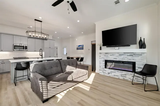 a kitchen with stainless steel appliances kitchen island granite countertop a refrigerator oven a sink dishwasher and white cabinets with wooden floor