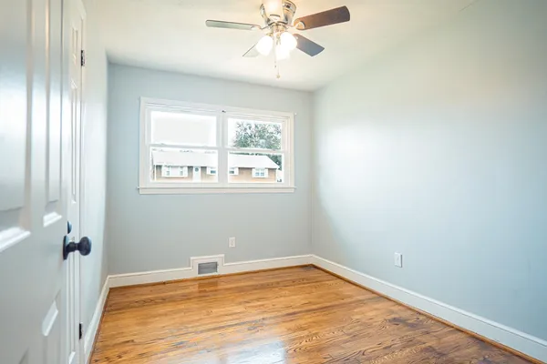 a view of a livingroom with a chandelier fan and wooden floor