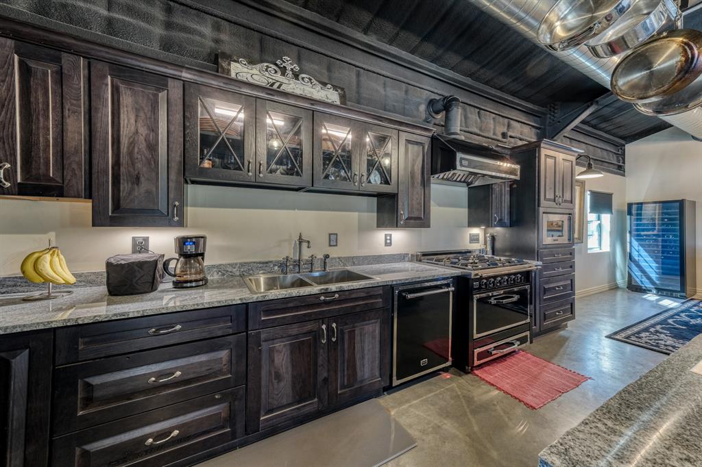 2337 Walsh Road Olney, TX 76374 - Photo 27 of 38 Kitchen featuring dark wood cabinetry, light-colored countertops, a stainless steel sink with a gooseneck faucet, a built-in dishwasher, and a professional-grade range with a matching range hood