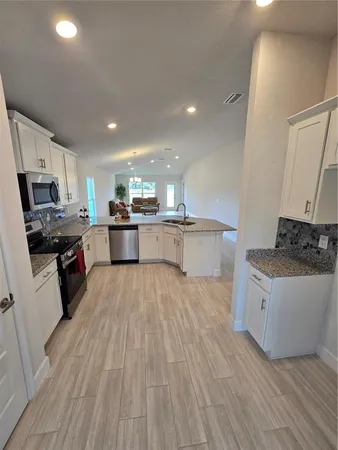 a kitchen with stainless steel appliances granite countertop a sink a stove and cabinets