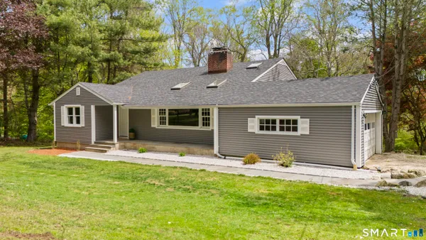 a front view of house with yard and trees in the background