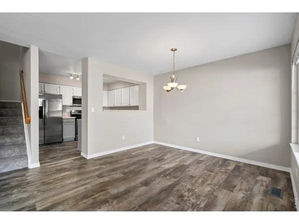 a view of an empty room with wooden floor fireplace and a window