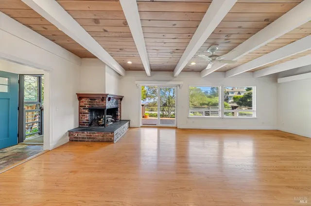 a view of a hall with wooden floor and a fireplace