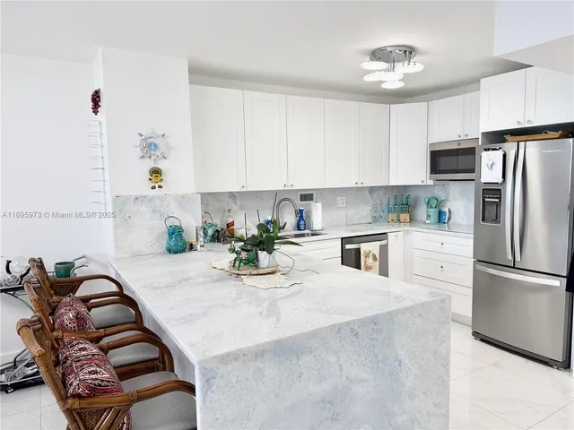 a kitchen with stainless steel appliances granite countertop a refrigerator a sink a stove and white cabinets