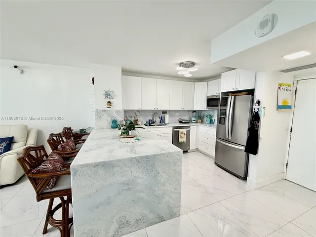 a kitchen with stainless steel appliances a refrigerator a stove a sink a dining table and chairs