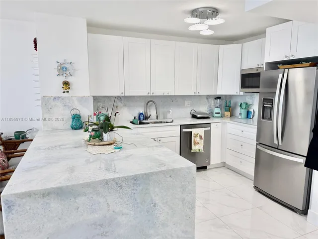 a kitchen with stainless steel appliances granite countertop a refrigerator sink stove and white cabinets