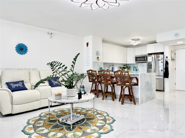 a living room with furniture potted plant kitchen view and a table
