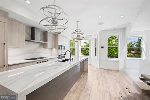 a kitchen with stainless steel appliances granite countertop a stove oven and a large window with wooden floor