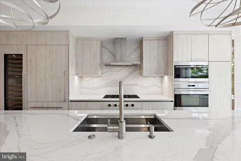 a kitchen with kitchen island a stove and a refrigerator with white cabinets