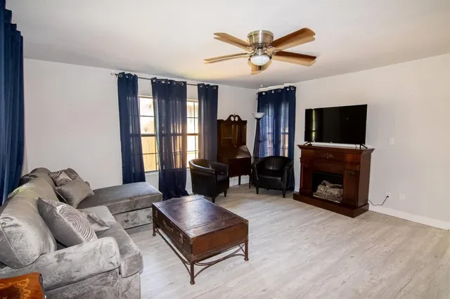 a living room with furniture a fireplace a flat screen tv and a large window