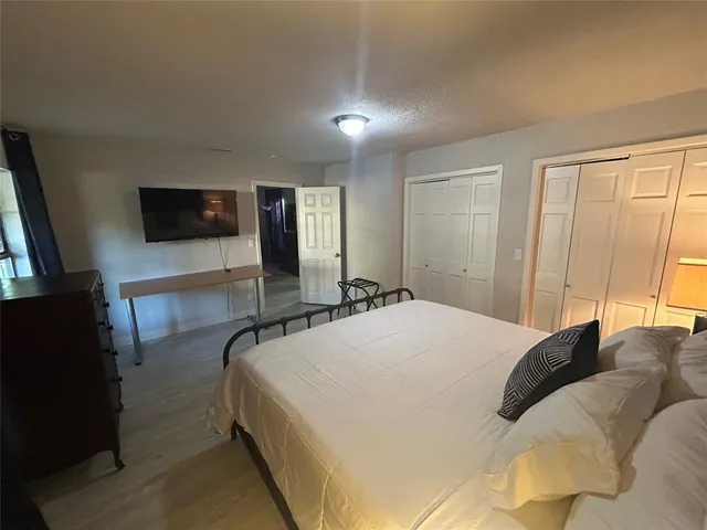 a spacious bedroom with a bed and a flat screen tv
