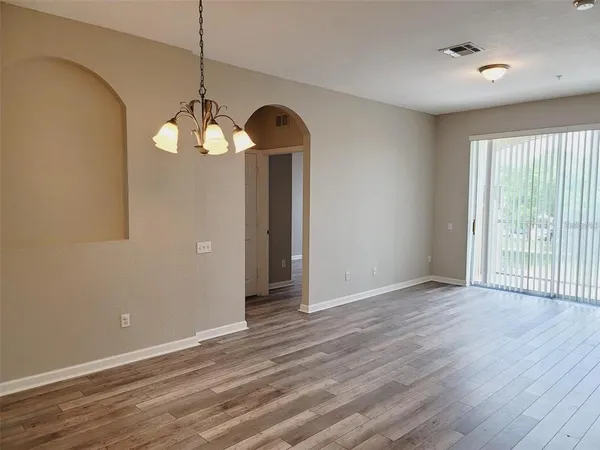an empty room with wooden floor fan and window