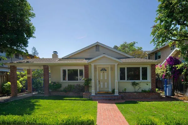 a front view of a house with a yard and potted plants