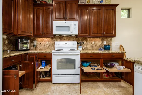 a kitchen with stainless steel appliances granite countertop wooden cabinets a stove and a sink