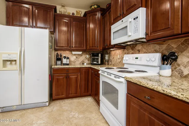 a kitchen with stainless steel appliances kitchen island granite countertop a refrigerator and a sink