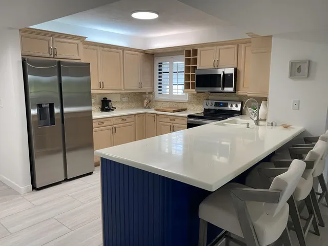 a kitchen with stainless steel appliances a refrigerator a sink a stove a table and chairs